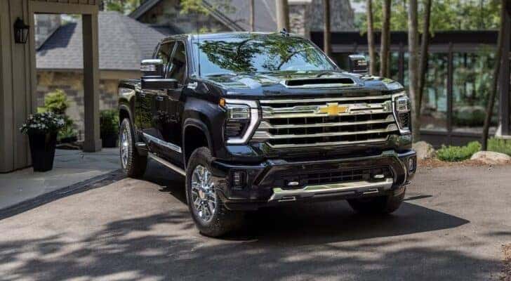 A black 2024 Chevy Silverado 3500 HD High Country is shown parked near a house after visiting a Chevy Silverado dealership near New Hope.