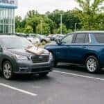 A realistic photograph of a well-kept late-model SUV parked on a clean dealership lot next to a new full-size Chevrolet SUV, a trade appraisal clipboard resting on the fender, bright overcast north Alabama morning light, wide 16:9 composition. No text, no logos other than natural vehicle badging, no identifiable faces. (Representative image for illustration purposes only. Actual vehicle may vary based on trim and configuration.)