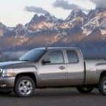Grey 2010 Chevrolet Silverado parked parallel to tall, snowy mountains