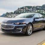 Black 2016 Chevy Malibu driving out of a mountainside town