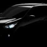 Black 2016 Chevrolet Spark parked in an all black, dark room with its headlights on