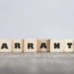 Brown letter blocks that spell out the word "WARRANTY" sitting on a brown surface