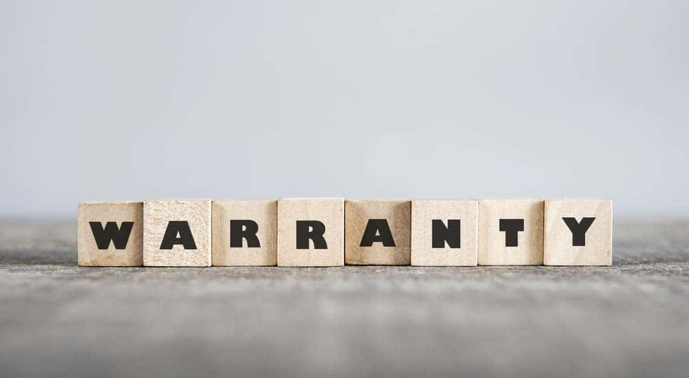Brown letter blocks that spell out the word "WARRANTY" sitting on a brown surface
