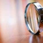 Silver and black magnifying glass sitting on its side on a brown wooden table
