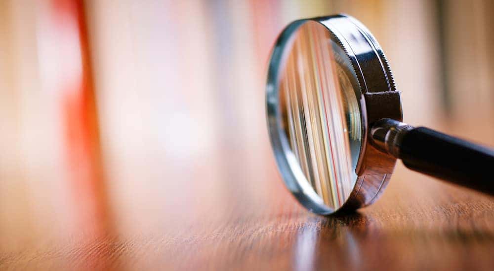 Silver and black magnifying glass sitting on its side on a brown wooden table