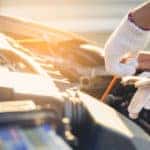 Mechanic, wearing a white glove on one hand, checking the oil of a vehicle