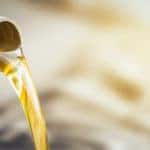 Oil pouring into the oil tank of a vehicle from a grey bottle