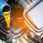 Oil pouring from a blue container into the oil tank of a vehicle