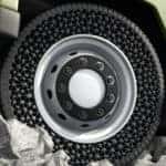 Black airless tire on a green vehicle driving over grey rocks