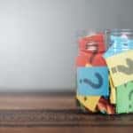 Various colors of scrap paper with black question marks on them in a clear glass drawer on a brown table