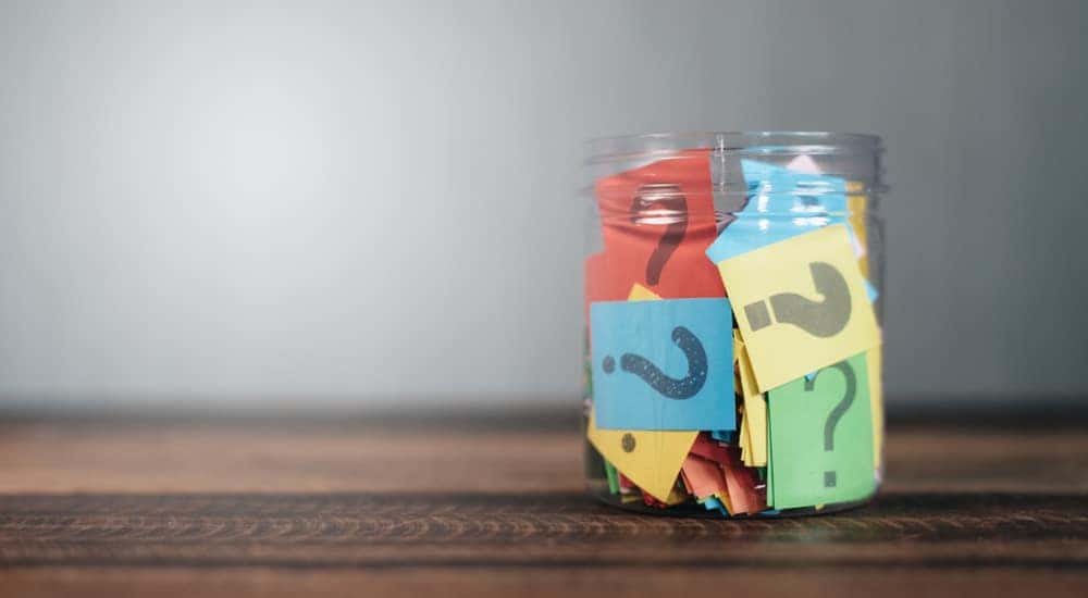 Various colors of scrap paper with black question marks on them in a clear glass drawer on a brown table