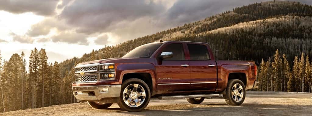 Side view of a maroon 2014 Silverado 1500 parked next to a cliff at dusk