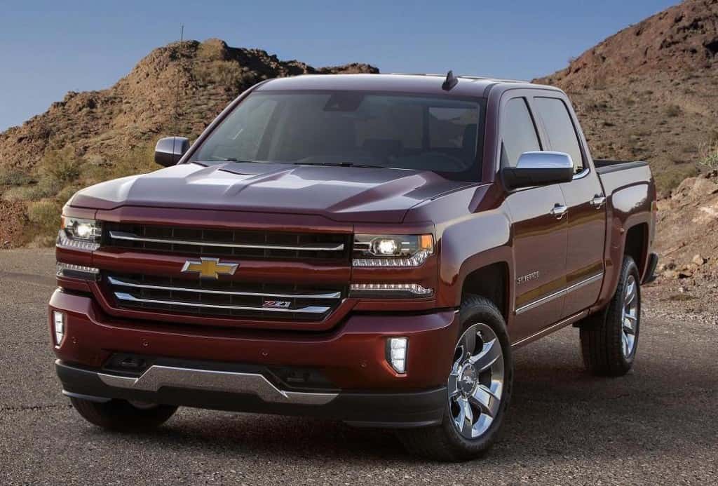 Red 2016 Chevy Silverado parked in front of dirt hills