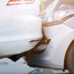 Silver car smashed into the side of a black car on a paved road