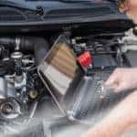Man in a white shirt using a computer to detect issues with a vehicle