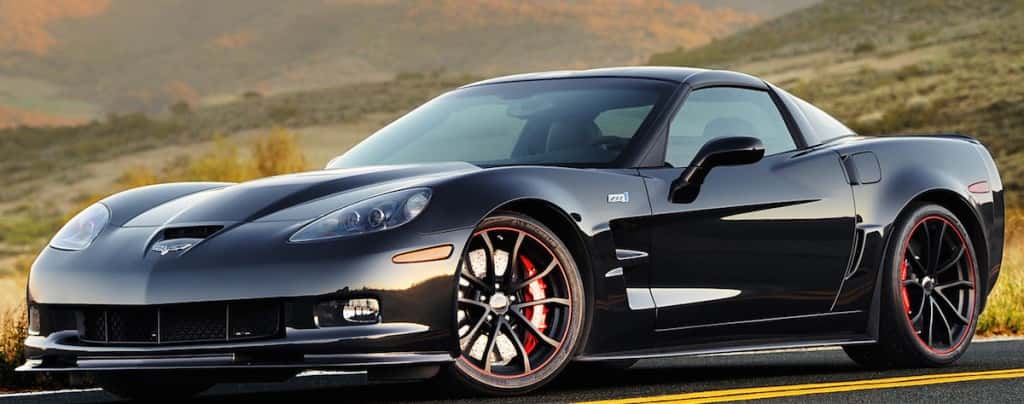 Side angled view of a black Chevy Corvette ZR1 parked in front of grassy hills