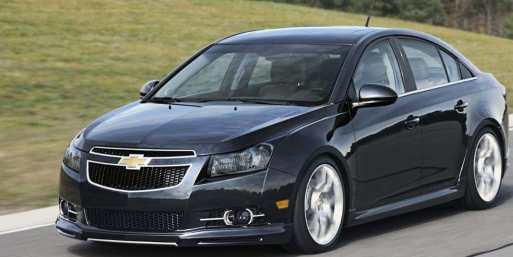 Side angled view of a black Chevy Cruze driving on an empty road