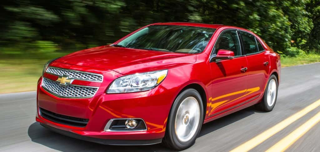 Front angled view of a red Chevy Malibu driving on an empty road