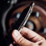 Hand holding a brake pad in front of a wheel