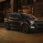 Black 2017 Chevrolet Equinox parked on the side of the road next to a brick building, at night