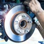 Mechanic inspecting brakes on a lifted vehicle