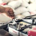 Hands using tools to work on a car battery