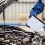 Man in a blue, white, and orange jumpsuit replacing the battery in a vehicle