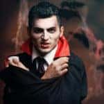 Vampire with a pale face wearing a black and red cape