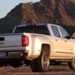 Silver 2015 Chevrolet Silverado 3500HD pickup truck parked in front of a tall dirt hill