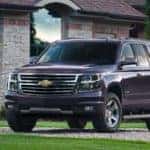 Purple 2016 Chevrolet Tahoe SUV parked in front of a brick and stone building