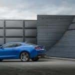 Blue 2016 Chevrolet Camaro sports vehicle parked on cement surrounded by tall grey walls