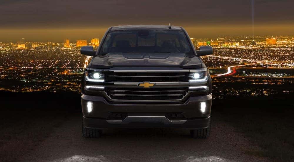 Dark-colored 2016 Chevrolet Silverado 1500 pickup truck parked in front of a lit-up city skyline
