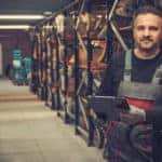 Man in grey and red overalls standing between the aisles at an auto parts store