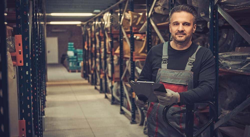 Man in grey and red overalls standing between the aisles at an auto parts store