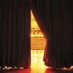 View of theater seats through a slightly open curtain