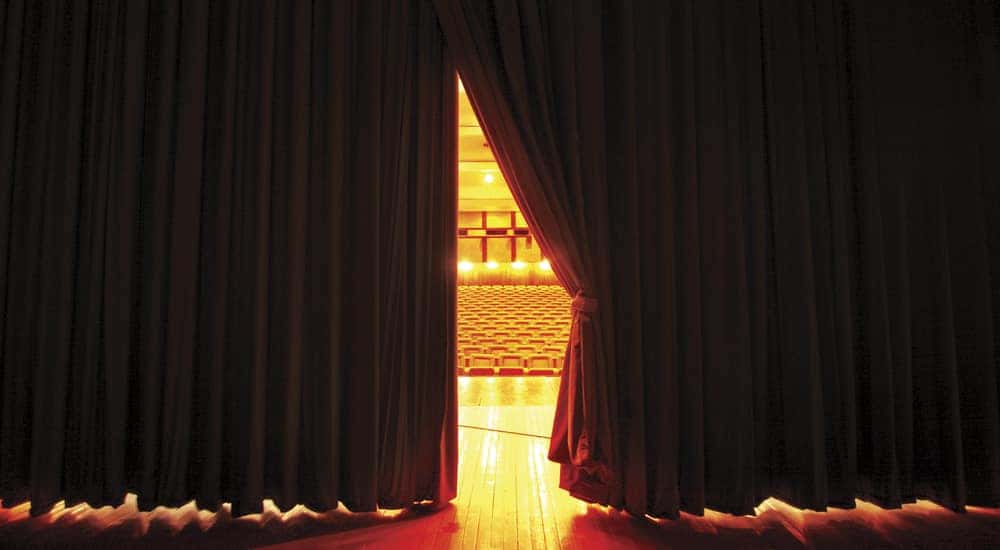 View of theater seats through a slightly open curtain