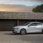 Silver 2017 Chevrolet Malibu sedan parked in front of three brown garage doors