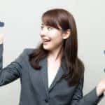 Businesswoman standing her hands out in front of a white wall with one hand below an "A" and one below a "B"
