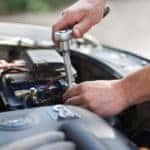 Mechanic working under the hood of a vehicle at an engine repair shop