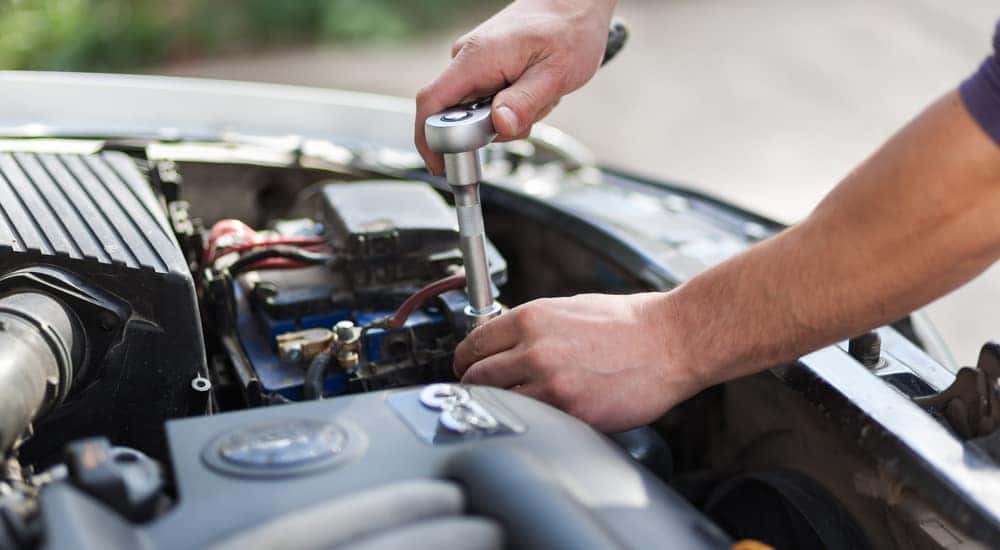 Mechanic working under the hood of a vehicle at an engine repair shop