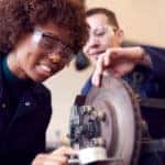 Female and male students working on vehicle brakes in a mechanic apprenticeship course
