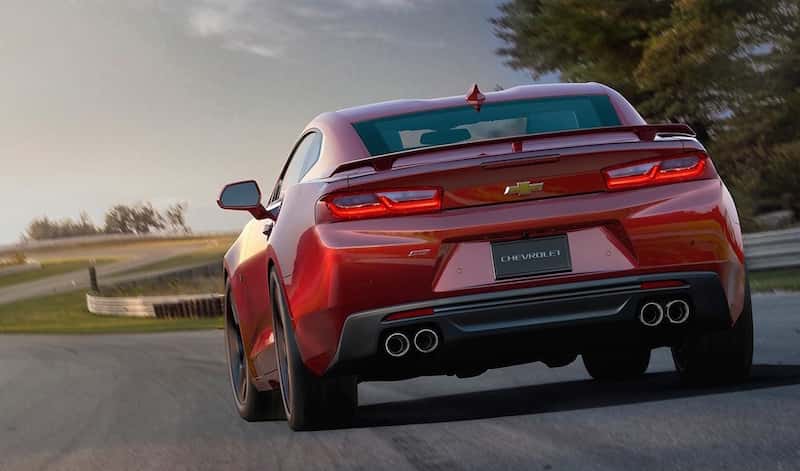 Rear view of a red 2016 Chevy Camaro SS speeding through a race track