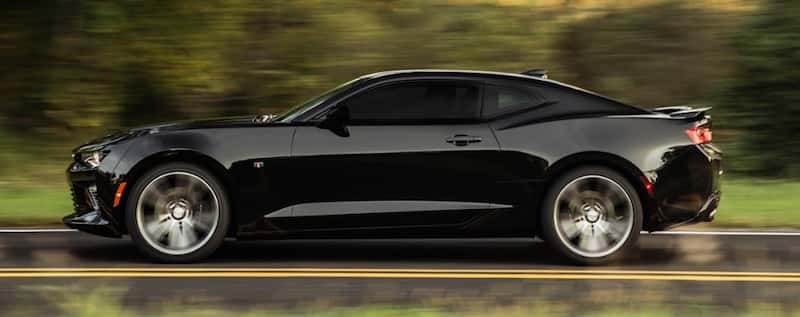Side view of a black 2016 Chevy Camaro driving down an open road