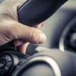 Hand wrapped around a vehicle's black steering wheel