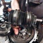 Mechanic in black overalls performing a car transmission repair