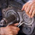 Mechanic in a blue shirt holding a tool and performing a transmission repair service
