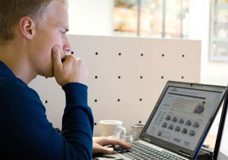 Man in a blue sweater researching vehicle trade-ins