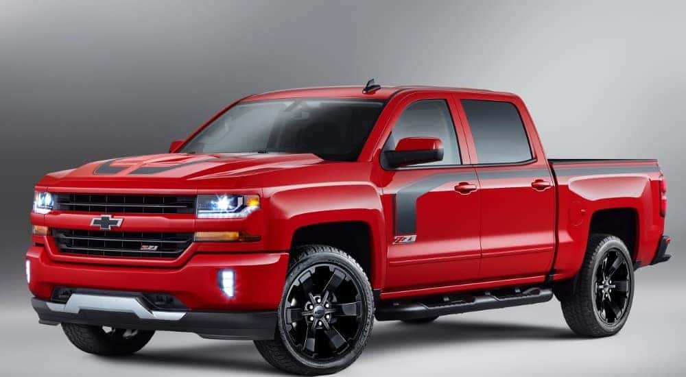 Red and black 2016 Chevy Silverado truck parked in a grey room