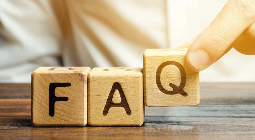 Brown blocks with black letters that spell out "FAQ" being placed on a brown table