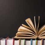 Open book on top of many books standing up straight